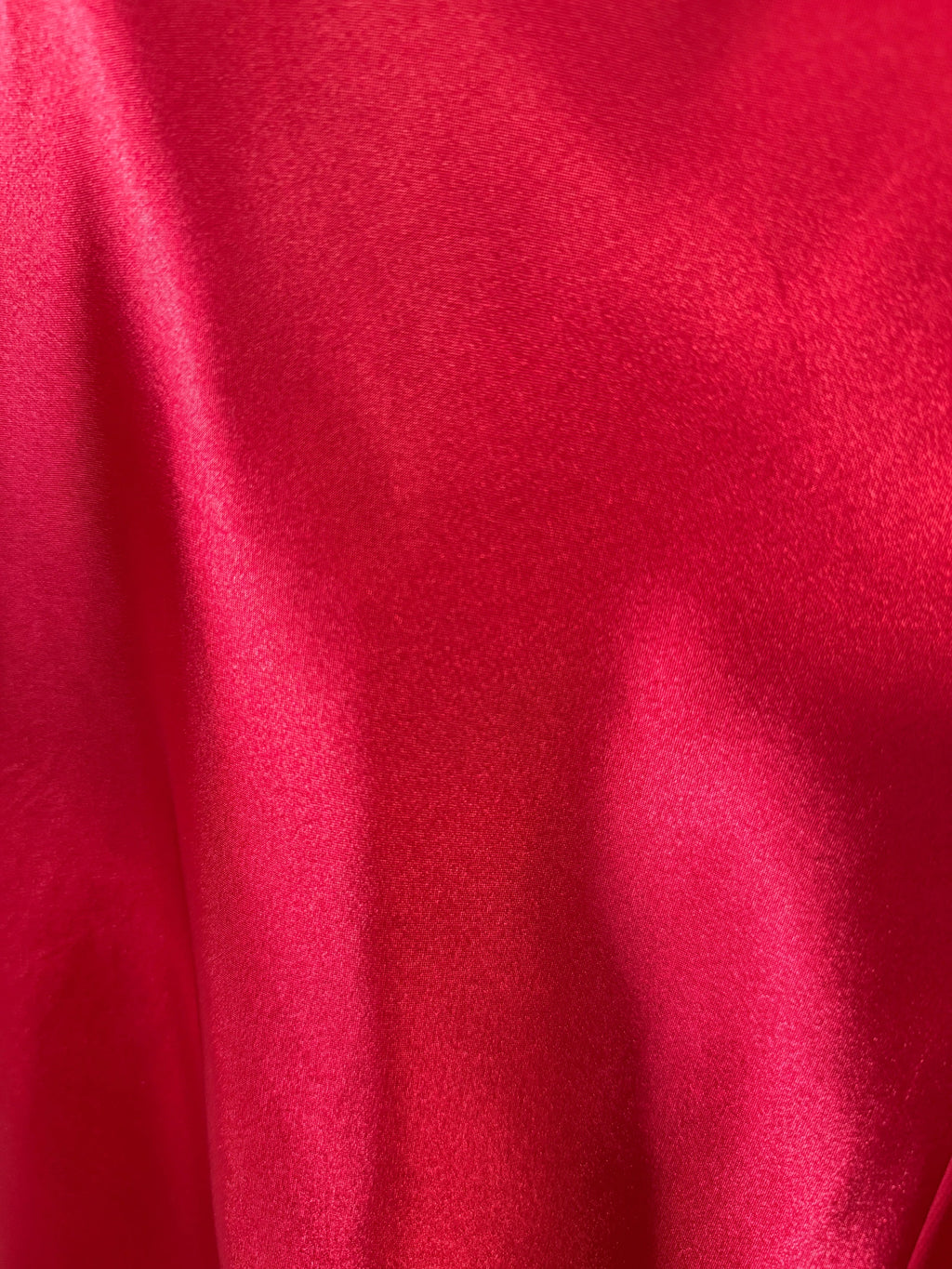 Close-up of the smooth red satin fabric from an Orvaniwear Betsy & Adam halter gown.