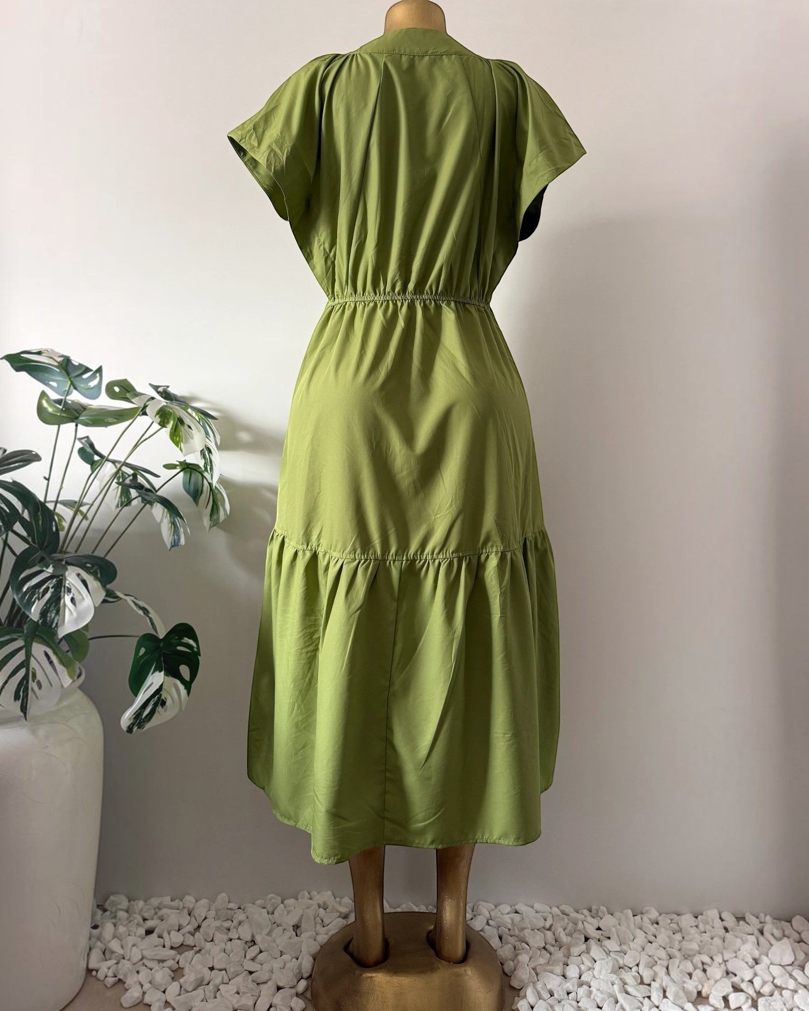 Back view of Orvaniwear olive green midi dress with cap sleeves, elastic waist, and tiered skirt on a mannequin.